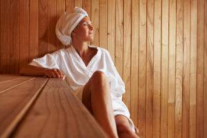 Ältere Frau sitzt entspannt in einer Sauna aus Holz