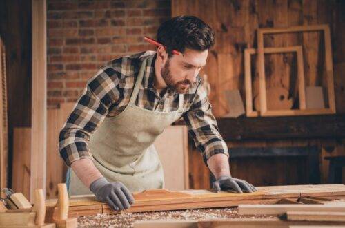 Möbelbauer in einer Werkstatt konzentriert bei der Arbeit, um maßgeschneiderte Möbelstücke in Berlin anzufertigen – Berlin Möbelbau