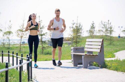 Personal Trainer trainiert mit einer Kundin beim Joggen im Park in Köln