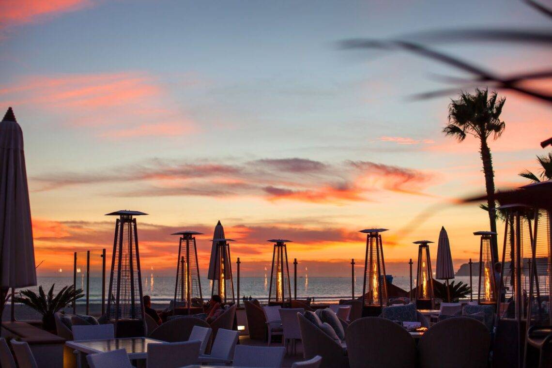 Sonnenuntergang auf Ibiza mit Blick auf ein Restaurant Ibiza, stilvolle Heizstrahler, Palmen und einem malerischen Himmel in warmen Farben