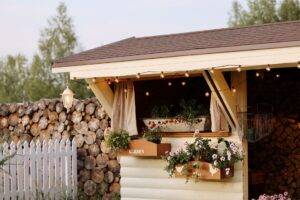 Gartenhaus mit Brennholz und Blumen vor Holzlager