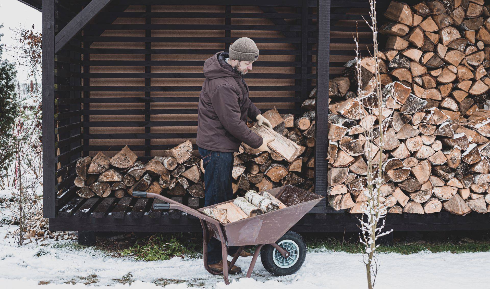 Kaminholzregal mit Holzvorrat im Schnee