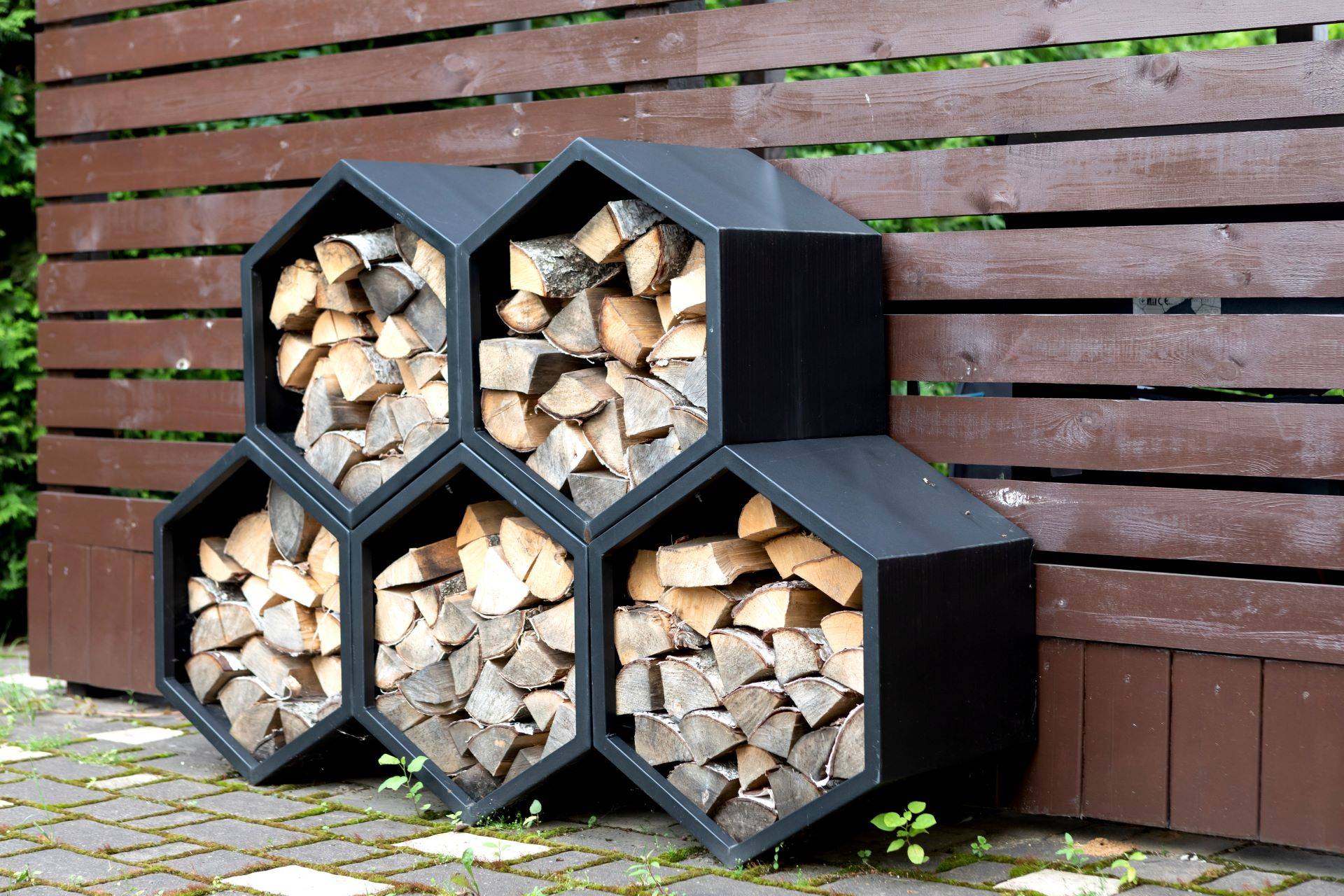 Modernes Metallregal mit Kaminholz im Freien