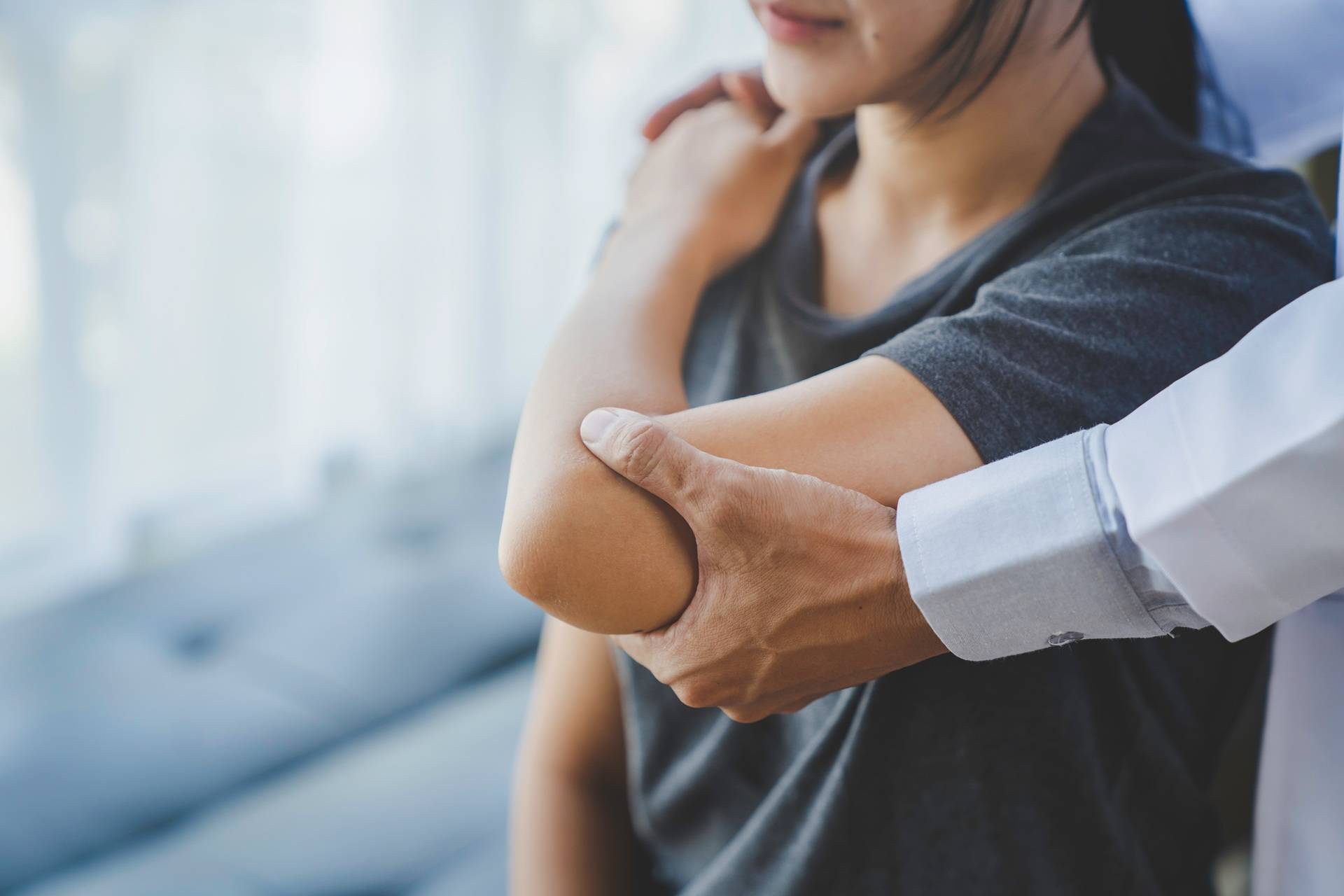 Arzt untersucht Ellenbogen eines Patienten | Orthopäde Köln