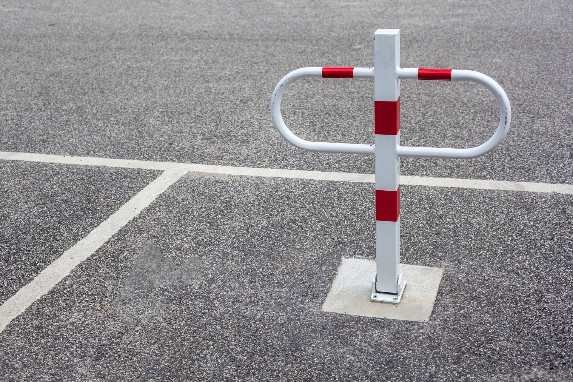 Weiß-roter Absperrbügel auf asphaltiertem Parkplatz | Parkplatzsperre