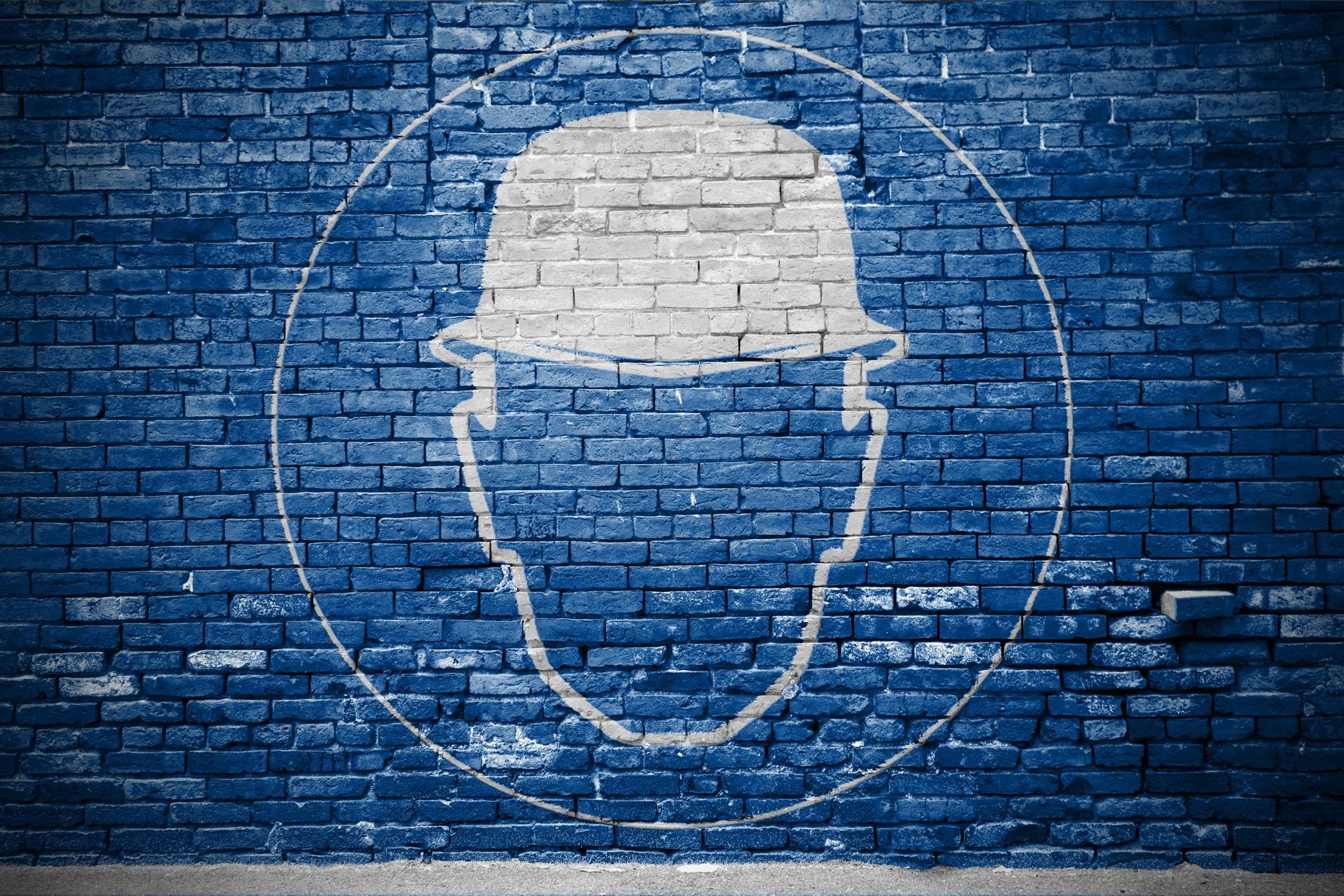 Weiße Schutzhelmgrafik auf blauer Ziegelwand | Fachkraft für Arbeitssicherheit Leipzig